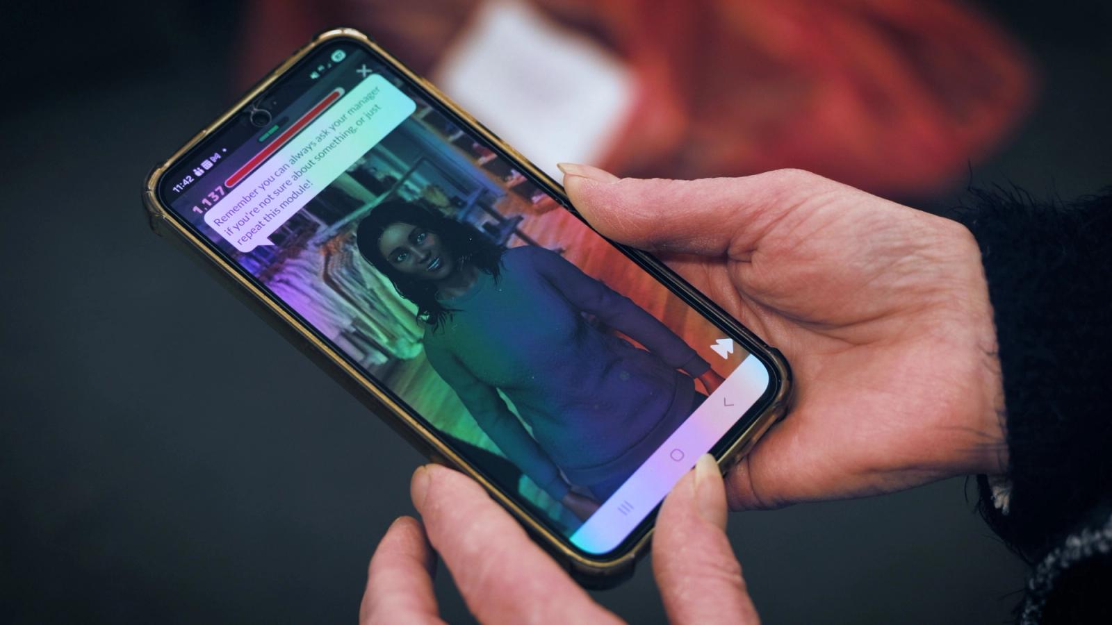 Hands holding a phone showing a simulation with a character in a shop and an instruction bubble