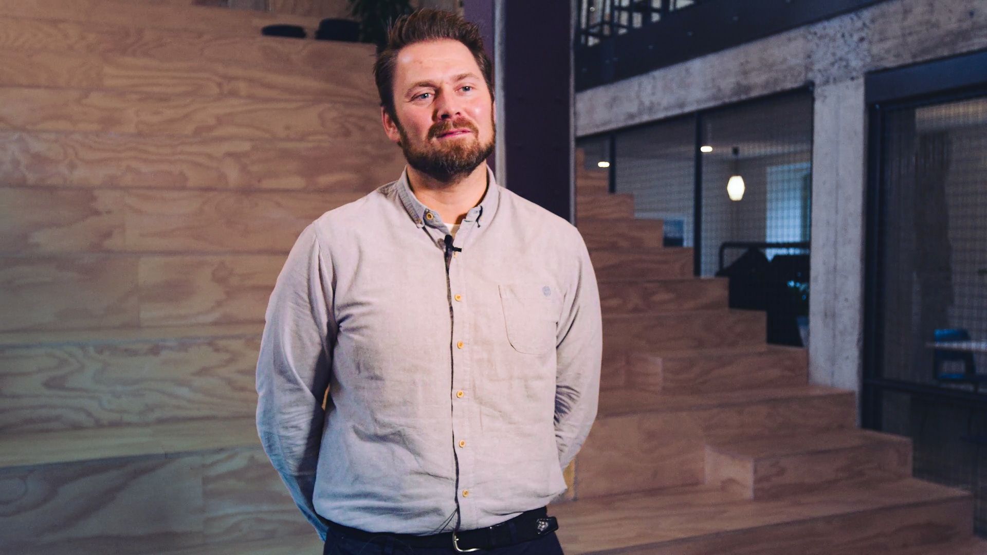Erik Bakstad standing in front of a plywood wall and staircase in an open office
