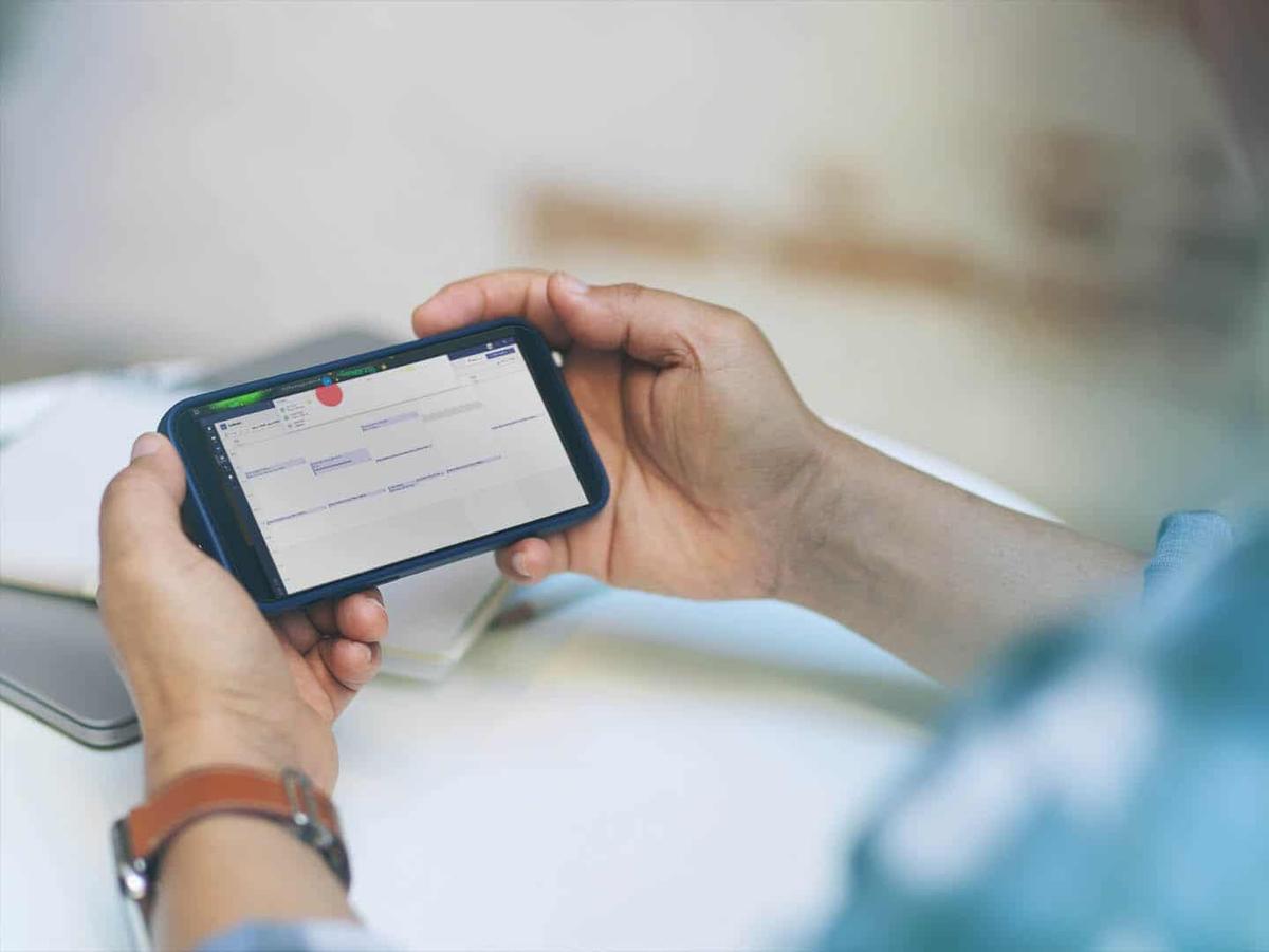 Cropped shot of male hands using horizontal smartphone while sitting in office room