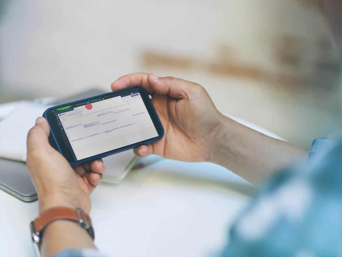 Cropped shot of male hands using horizontal smartphone while sitting in office room