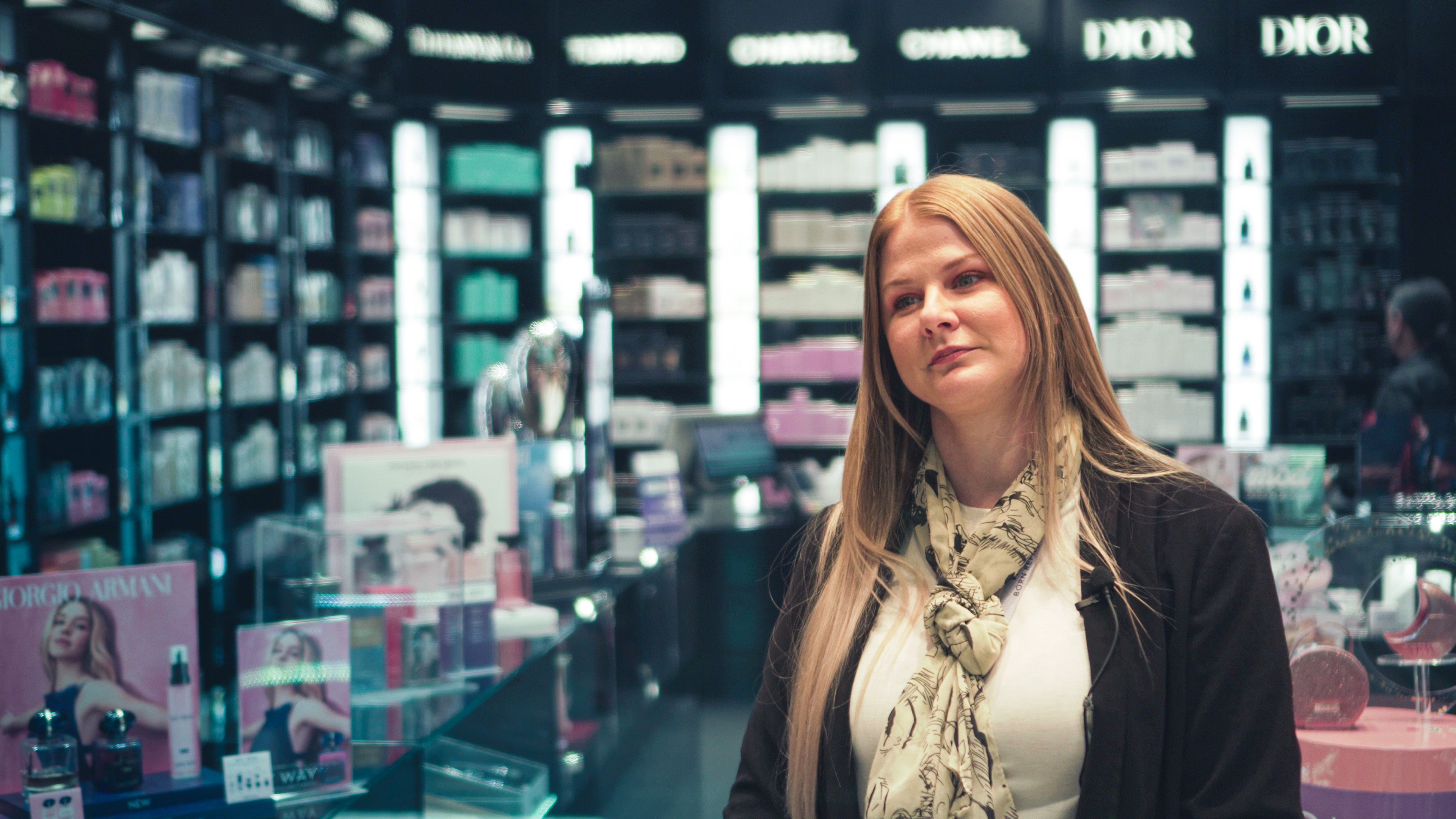 Angeline Ingram standing in a perfume shop in front of Chanel and Dior counters