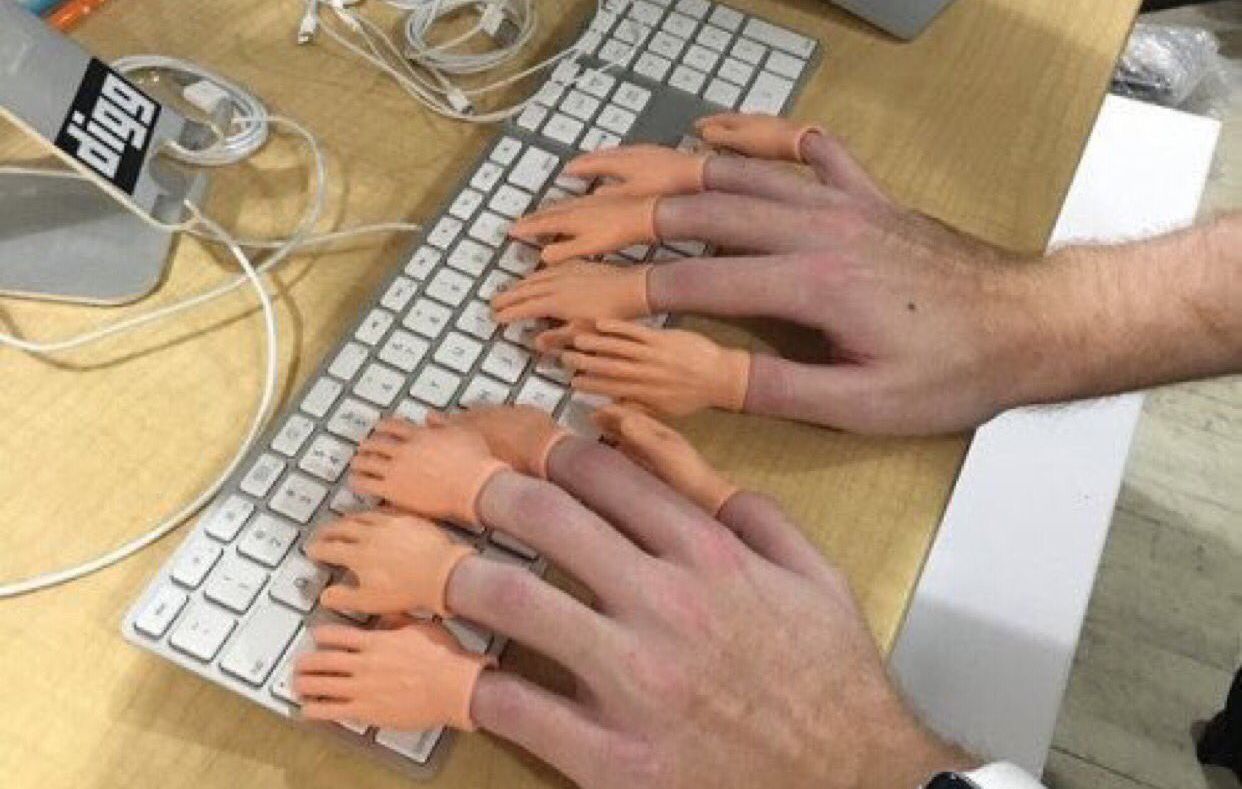 Dos manos tecleando en un teclado, cada una con diminutas manos de goma en los dedos
