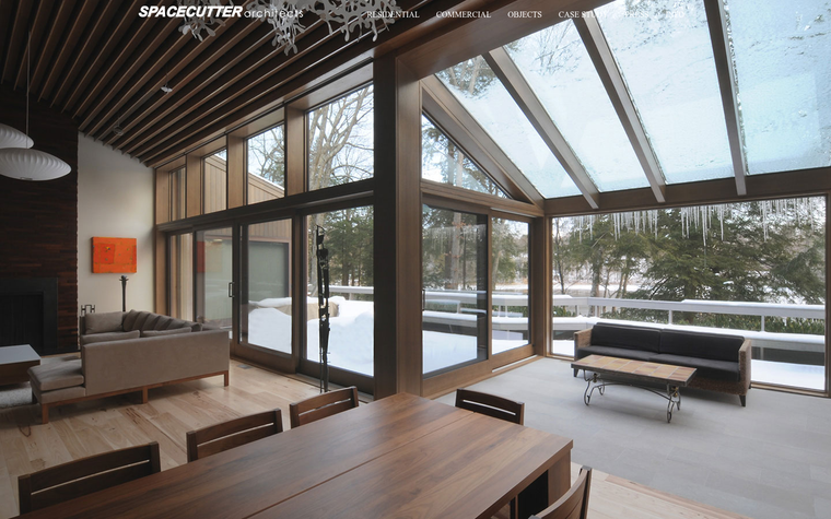 The SPACECUTTER Architects website at spacecutter.com, showing a timber living room under a glazed gable roof over a snowy garden