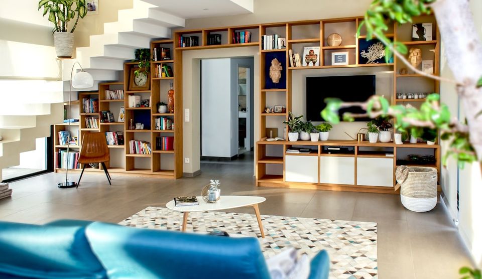 Bright, modern living area with built-in wooden shelves, potted greenery, and an open layout, illustrating sustainable interior design for eco-conscious clients.