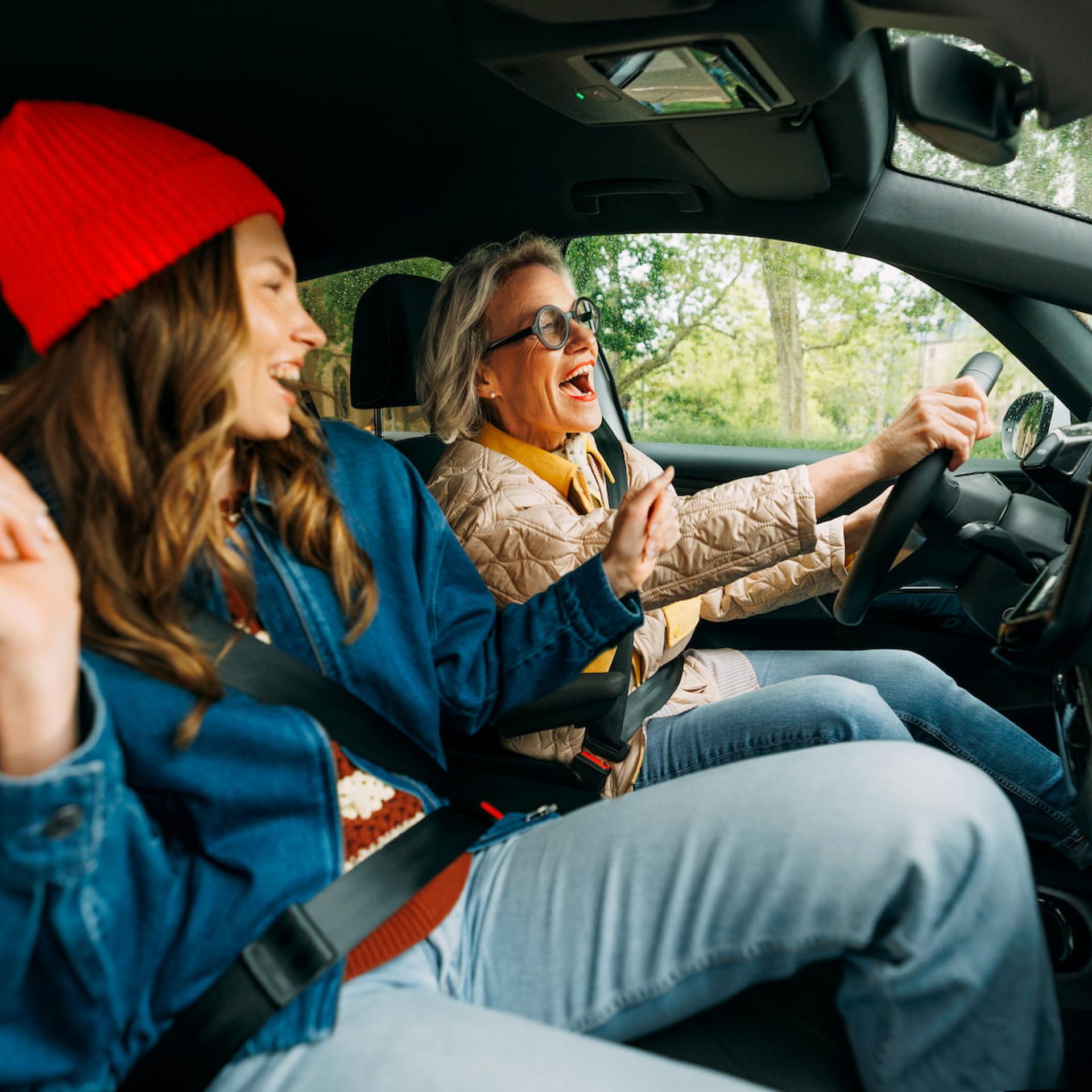 Jüngere und Ältere Frau singen gut gelaunt während sie in einem Auto fahren