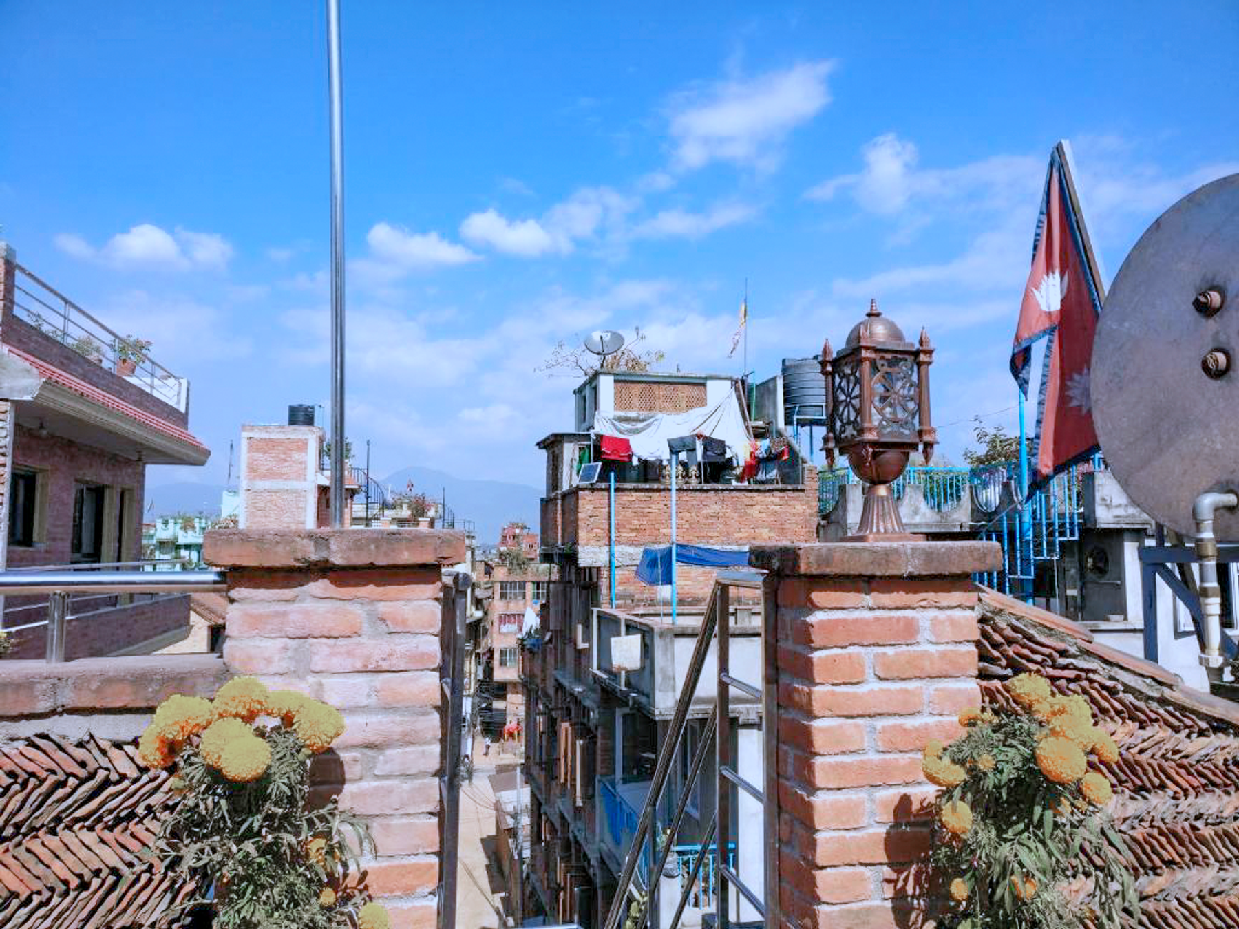 Patan rooftops beneath a blue sky seen from the shared terrace