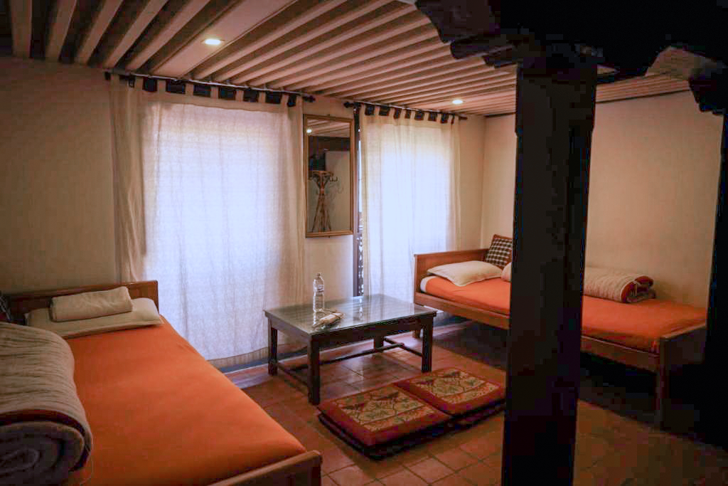 Brahmayani twin beds and a low table beside curtained windows