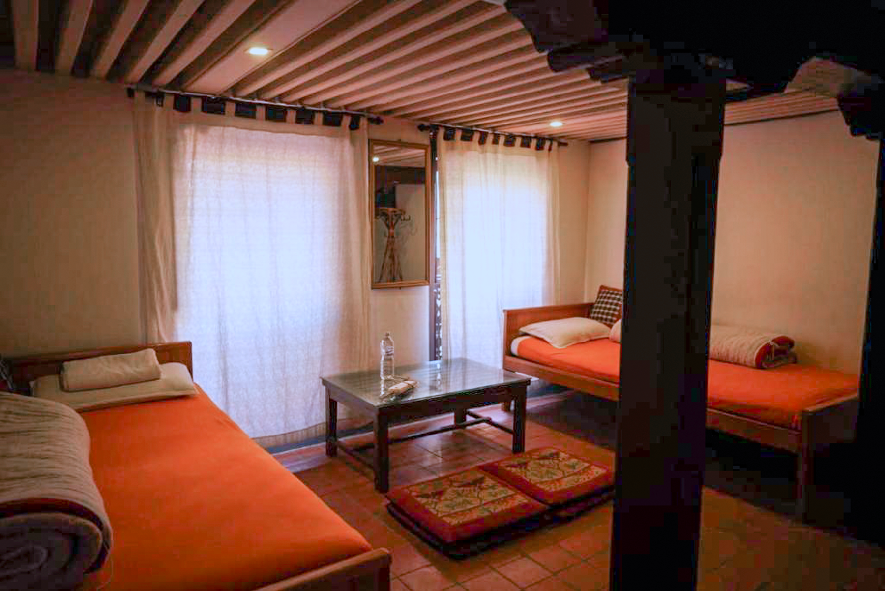Brahmayani twin beds and a low table beside curtained windows