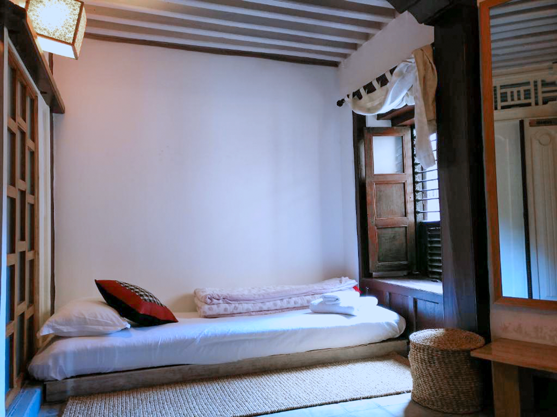 Kumari floor mattress beside a wooden window and mirrored wardrobe