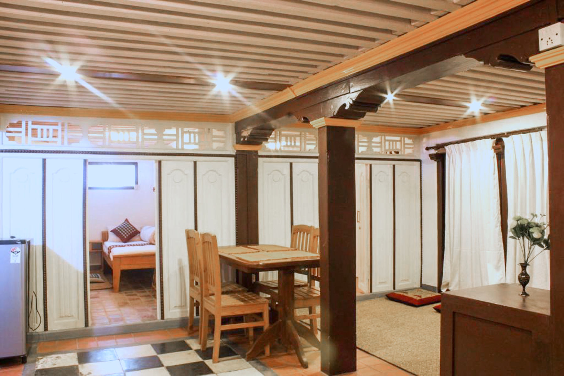 Shared dining area with a wooden table and chairs beneath exposed beams