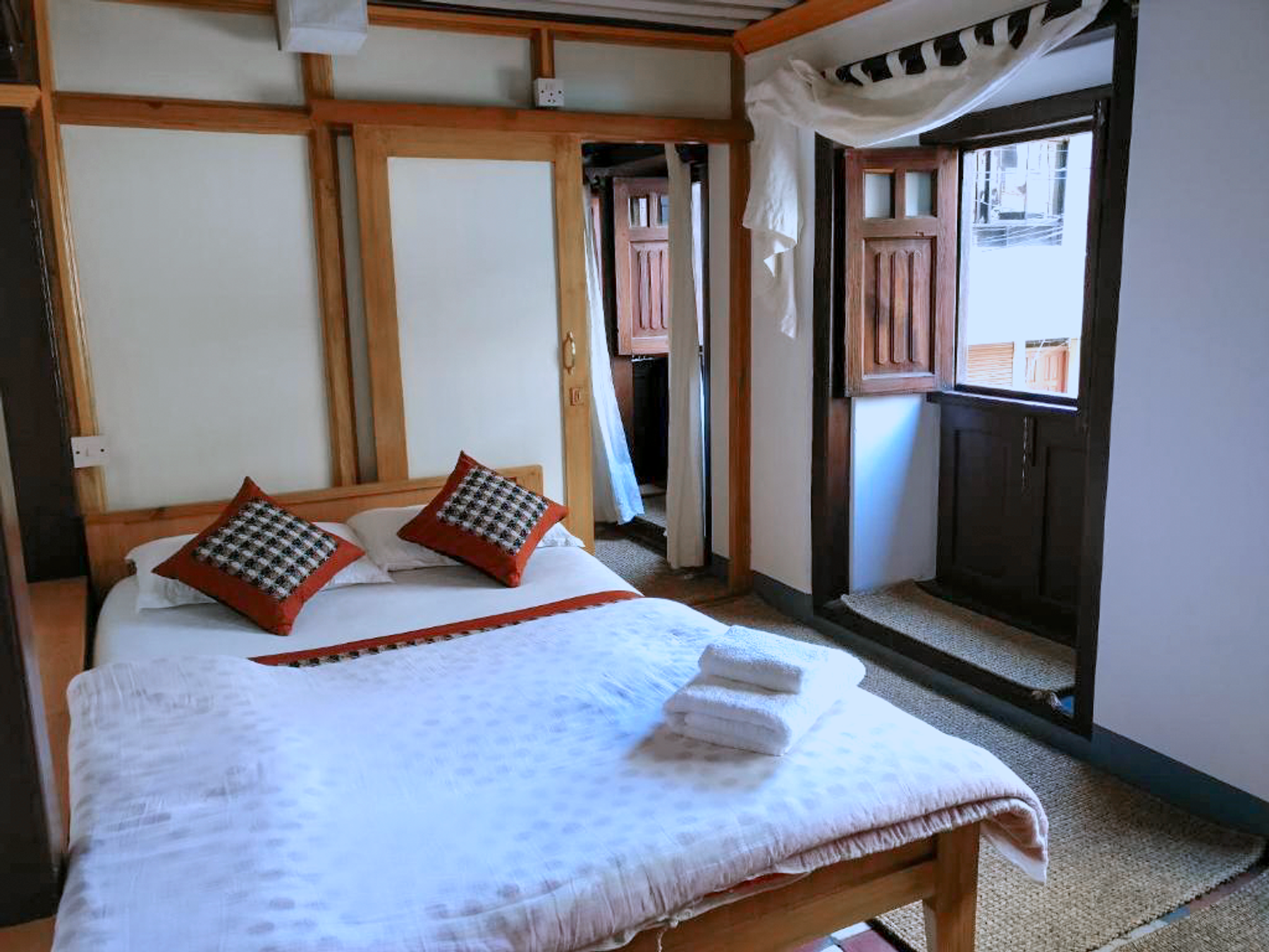 Vaishnavi double bed beside wooden windows and a small chair