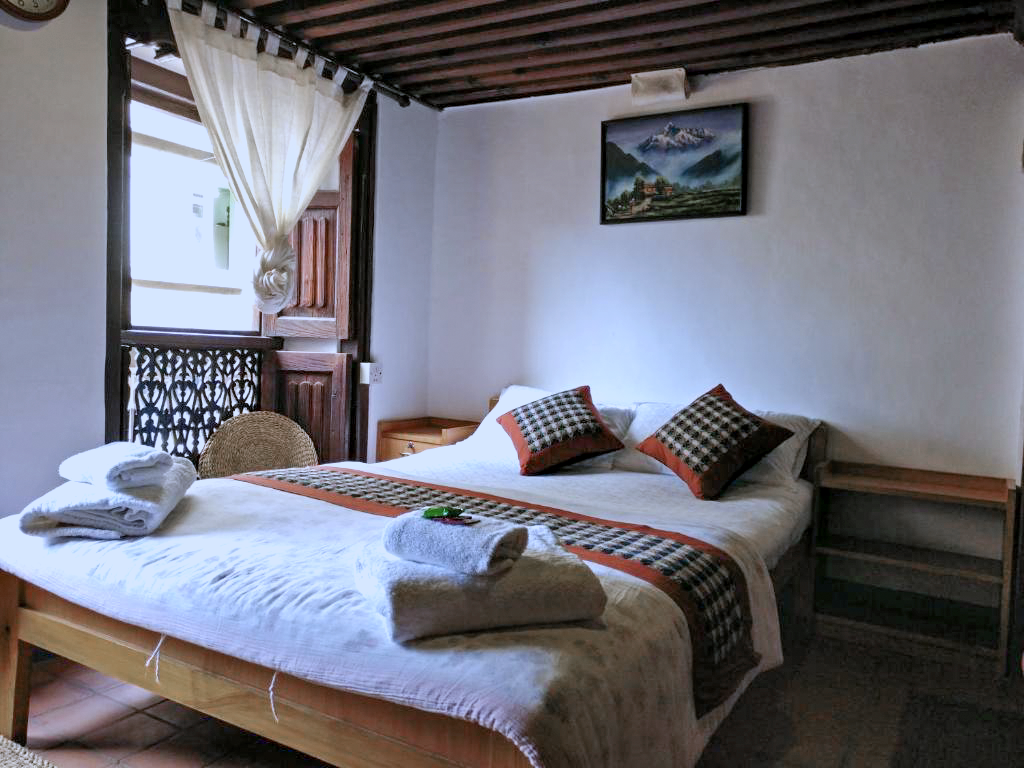 Rudrayani double bed with folded towels beside a wooden window
