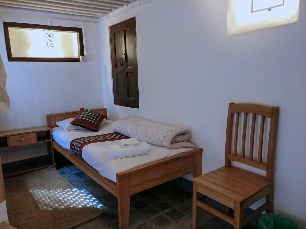 Kumari single bed with a bedside table and wooden chair