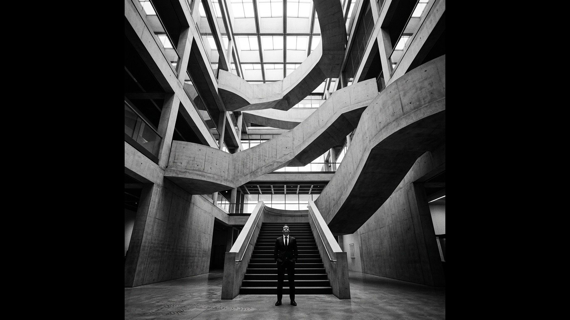 A lone executive looking up a complex concrete staircase