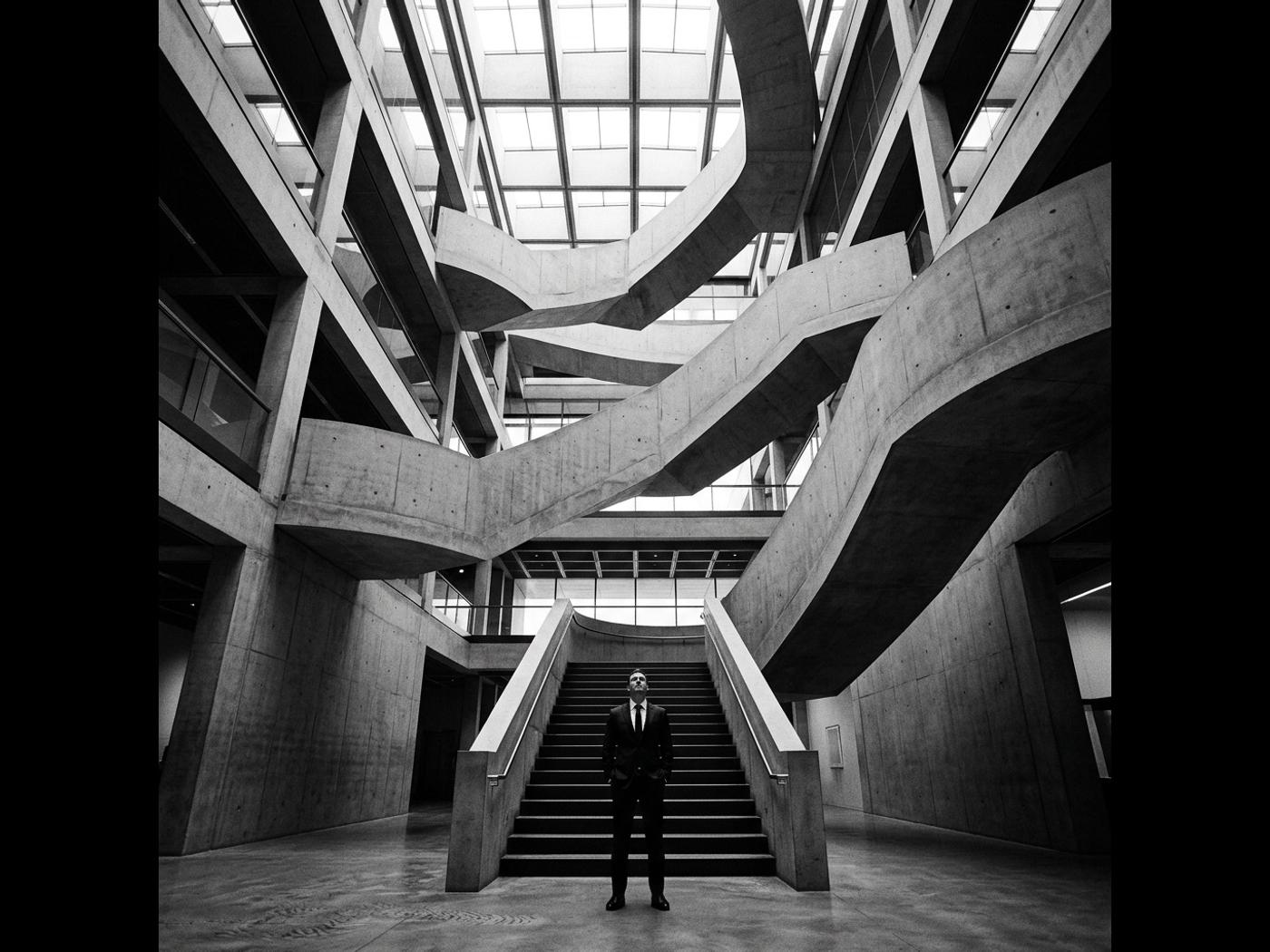 A lone executive looking up a complex concrete staircase