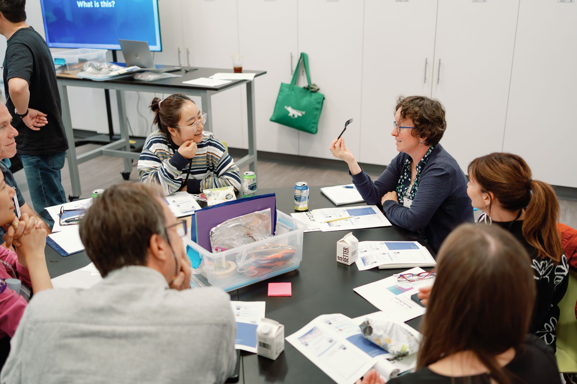 One participant gestures with a fork mid-project.