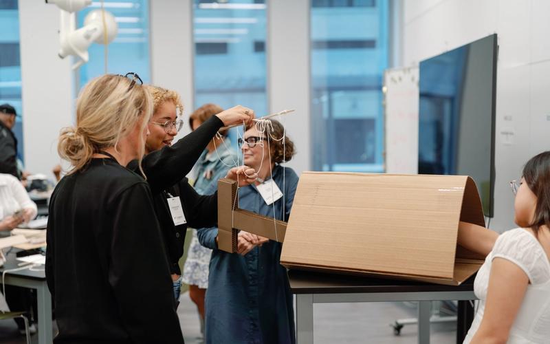 A team of educators work on their design project developed from cardboard and string.