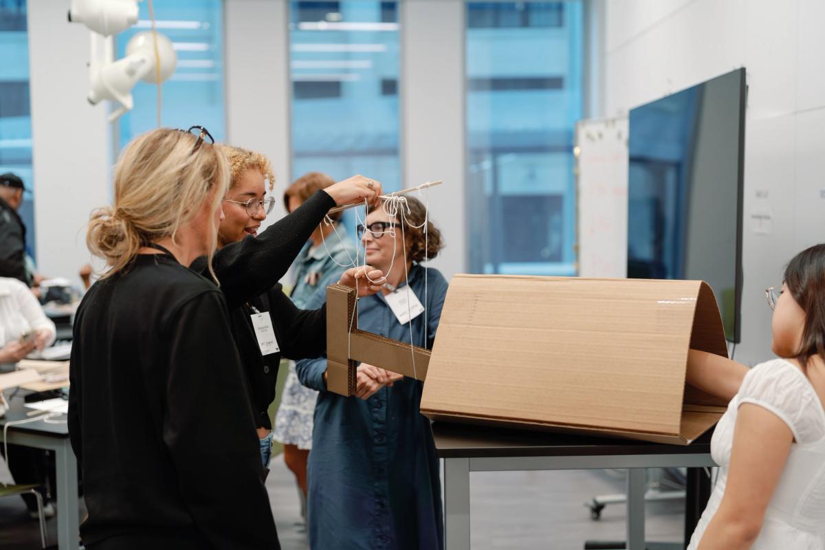 A team of educators work on their design project developed from cardboard and string.
