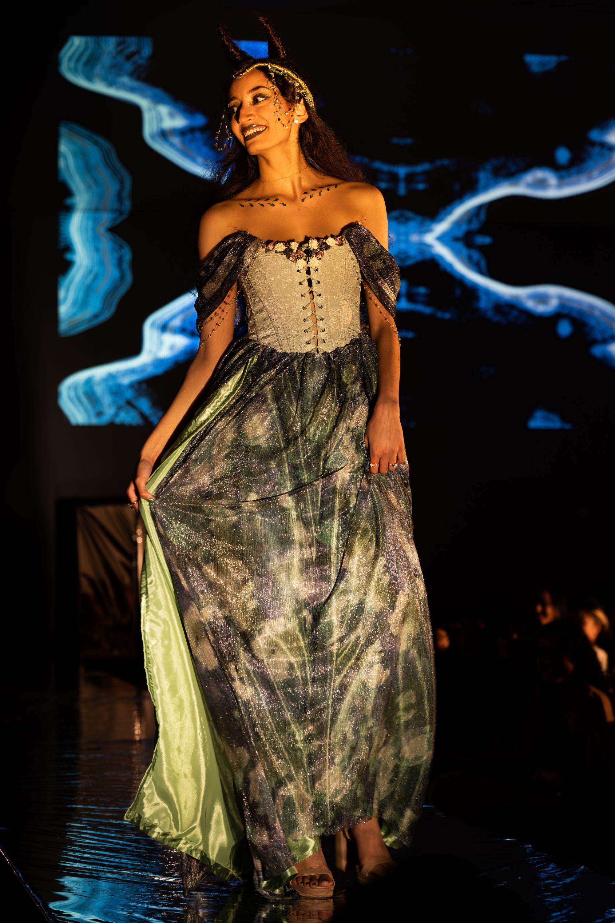 Taking two weeks to fabricate, “Gaea” is the first of Yoshi's Greek Goddess collection. A gown with a light green bodice and shimmery skirt, “Gaea” is accompanied by a green agate and braided wire headdress and self-modeled by Yoshi Ghosh ‘26 with hair styled into horns. Photo: Jules Dail