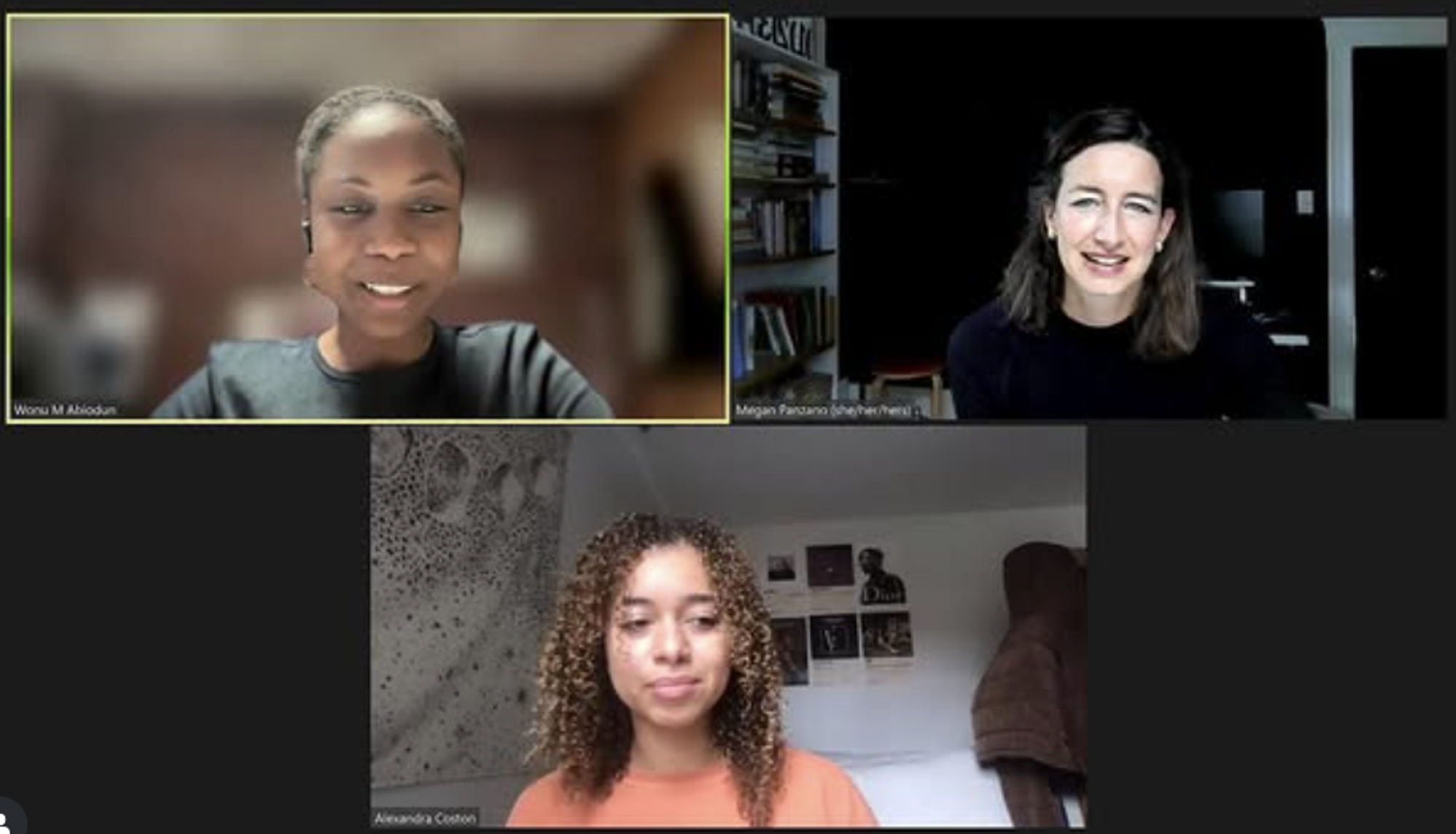 Screenshot of a three-person Zoom meeting. The top-left participant, identified as Wonu M Abiodun, is smiling and wearing a black top with an earpiece. The top-right participant, Megan Parzonko (she/her/hers), has shoulder-length dark hair and is smiling in front of a bookshelf and dark background. The bottom participant, Alexandra Coston, is sitting in a well-lit bedroom with curly hair and an orange sweater; there are posters and a tapestry on the wall behind her.