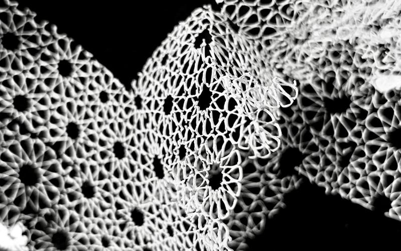 Intricate white geometric patterns resembling lace against a dark background, some in focus, some blurred.