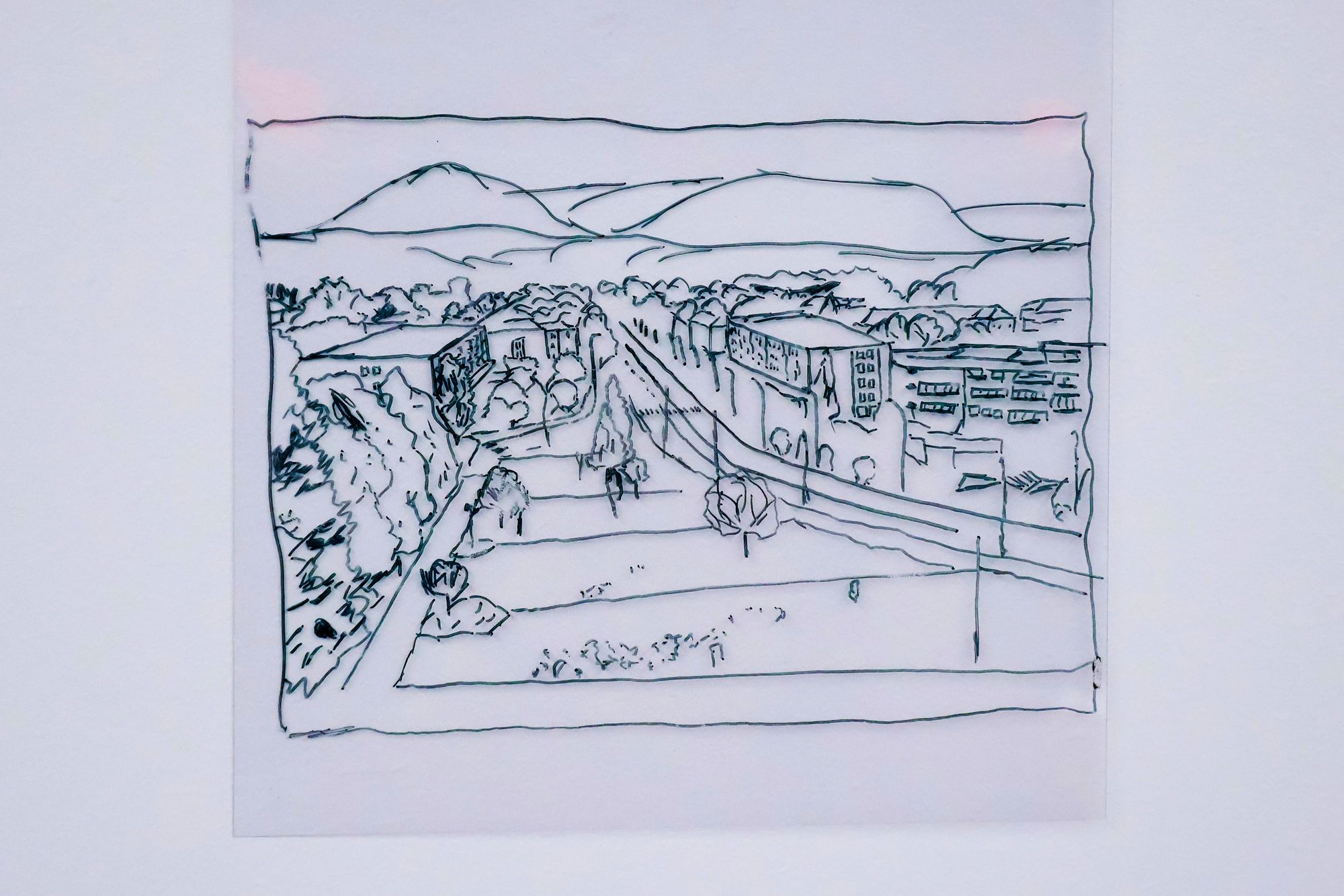 A hand-drawn black line illustration shows a cityscape with buildings, trees, and mountains in the distance, drawn on translucent paper.