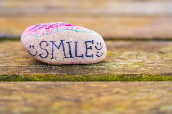 A stone with the words 'Smile' drawn on in pen