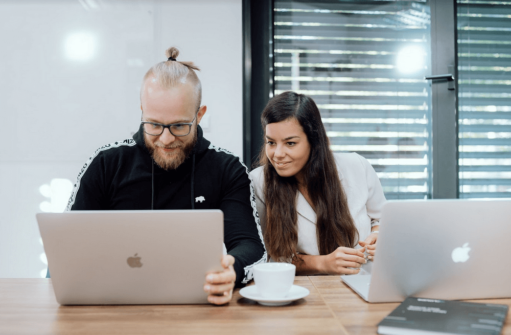 2 persons sitting in front of laptops