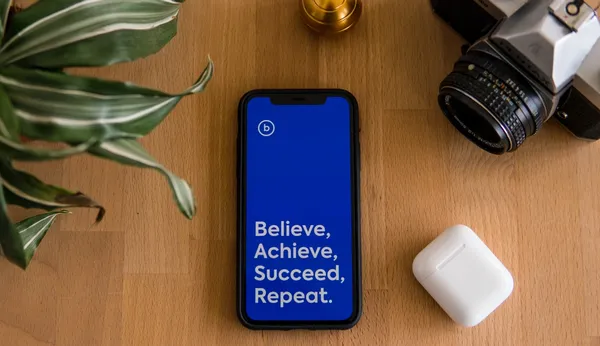 An iphone with a blue screen featuring the words: 'Believe, Achieve, Succeed, Repeat.'