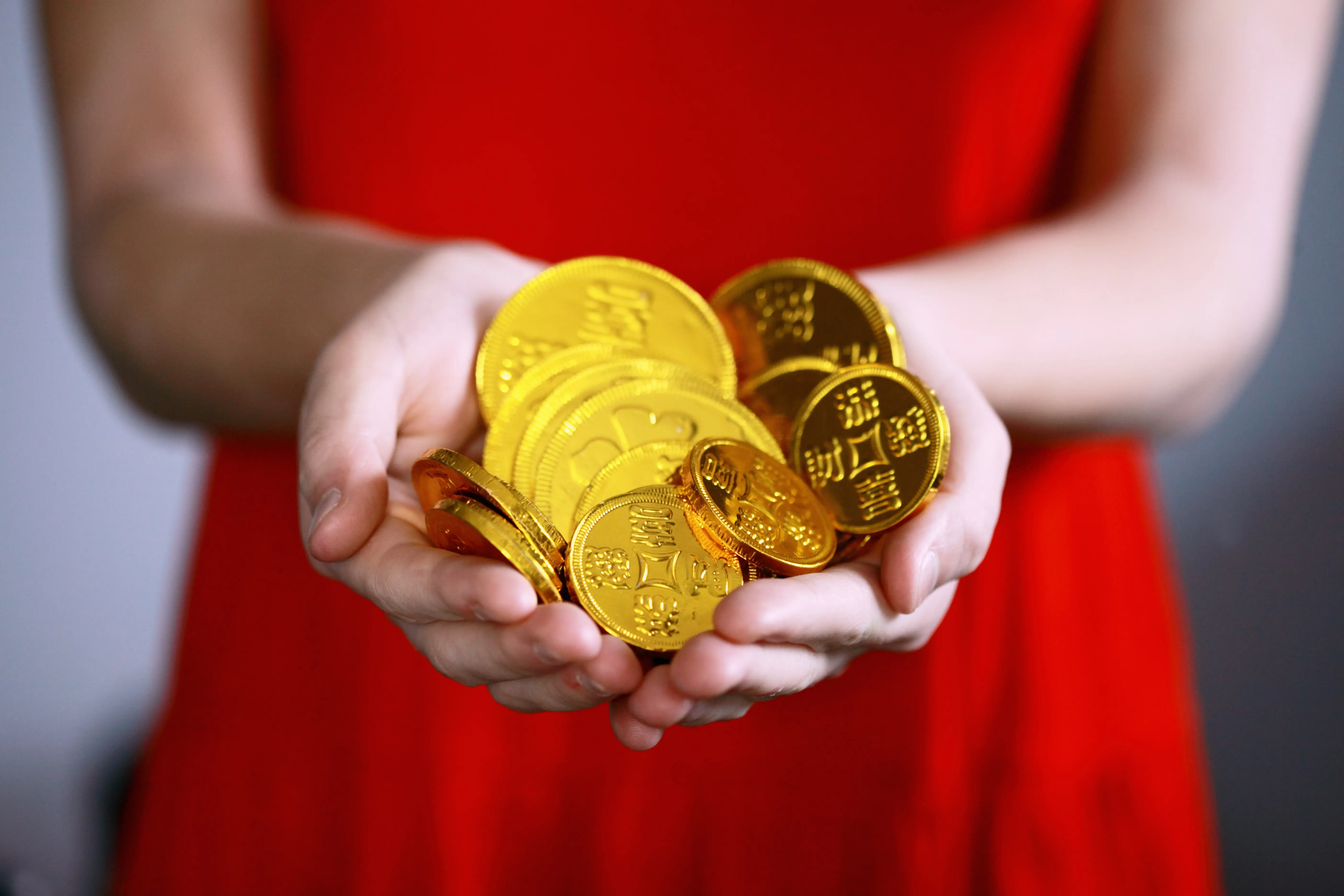 Woman in red dress holding a handful of gold coins