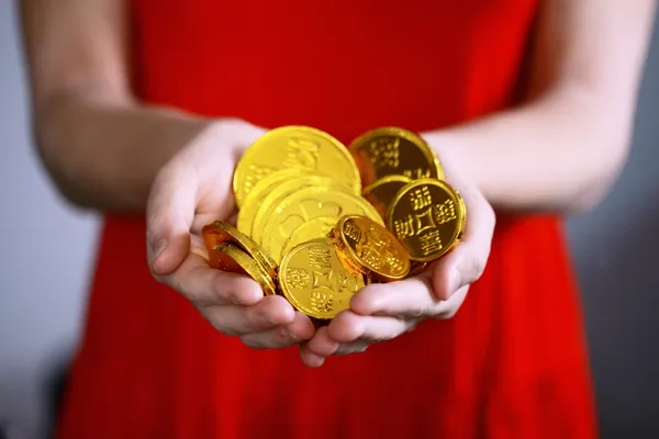 Woman in red dress holding a handful of gold coins
