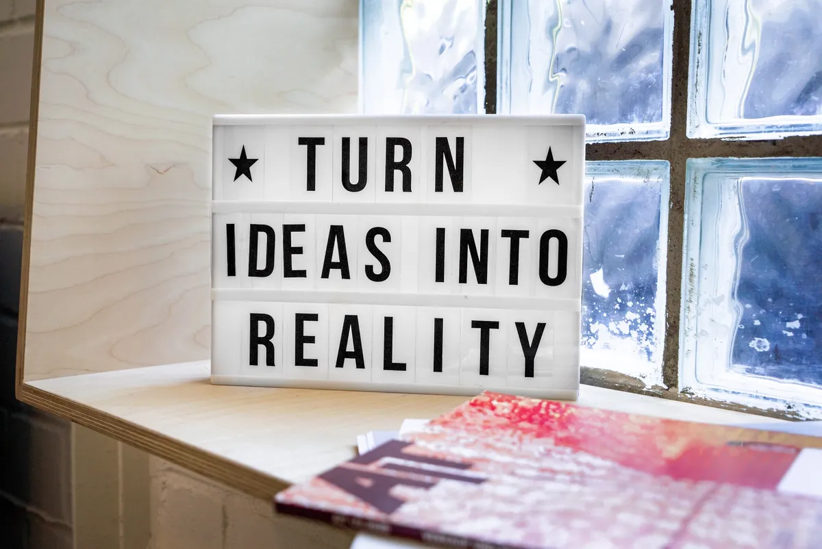 Image of a sign on a sunny windowsill saying 'Turn Ideas into Reality'