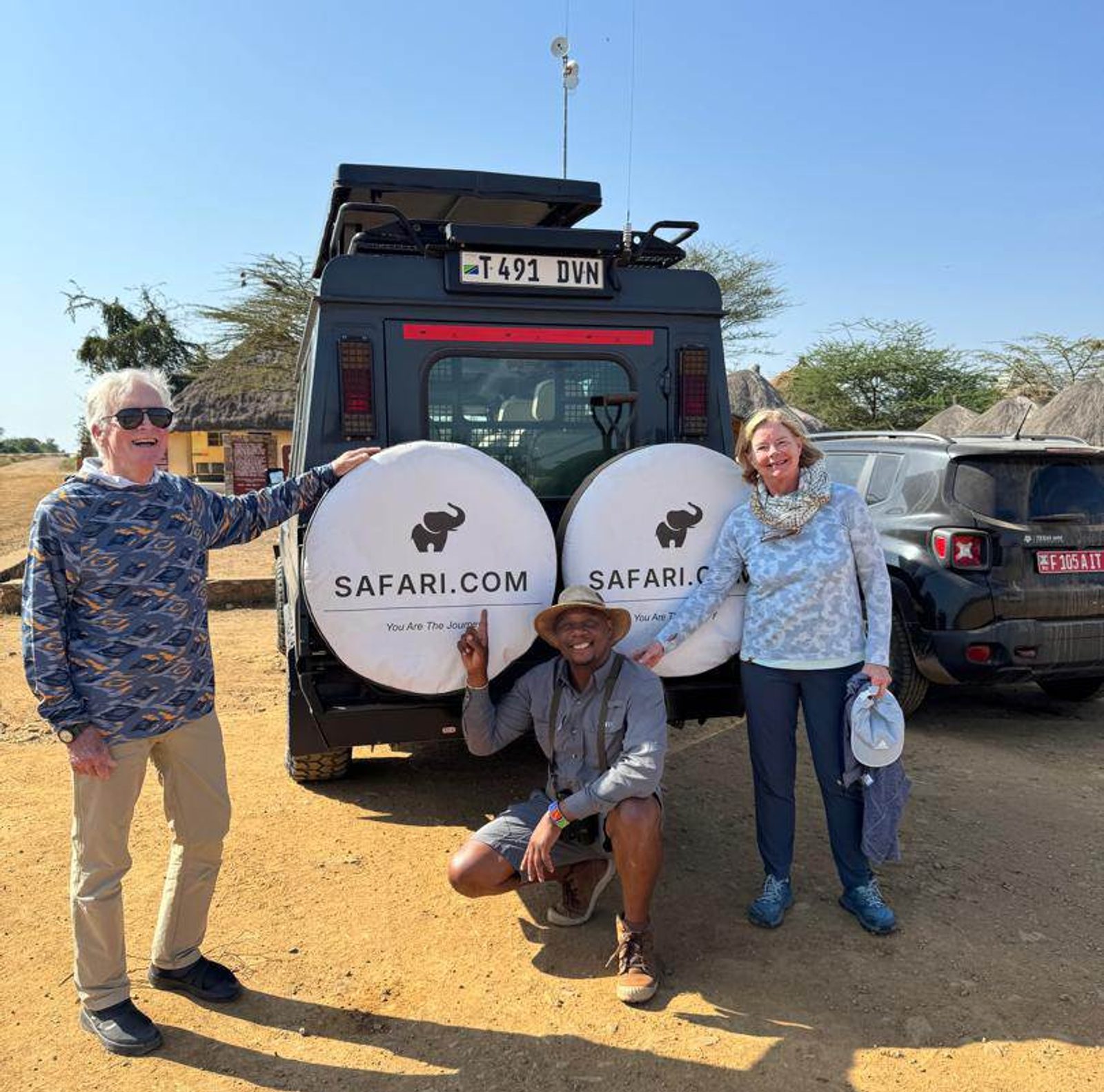 Guests beside a game-viewing vehicle with Safari.com-branded spare-wheel covers.