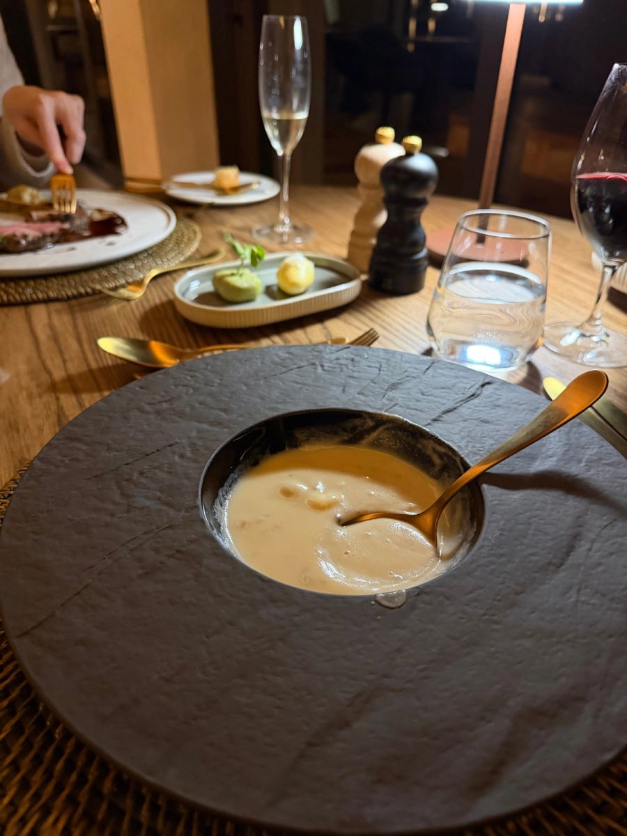 Celeriac soup served in a slate-grey stone bowl with a gold spoon at dinner at Kuganha