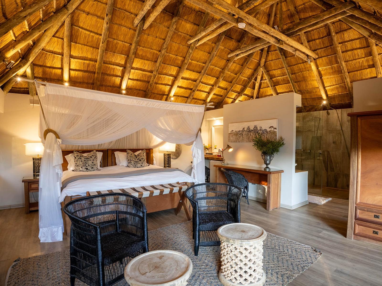 A four-poster bed under a soaring thatched roof in a suite at River Safari Lodge