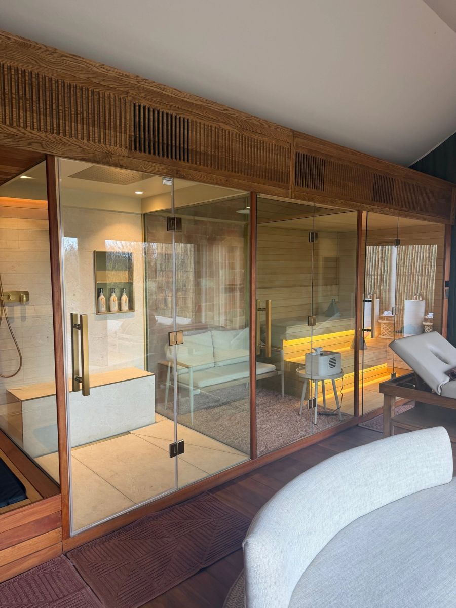 Glass-fronted in-suite spa wing at Kuganha showing the steam shower, Himalayan salt room, sauna and a massage bed