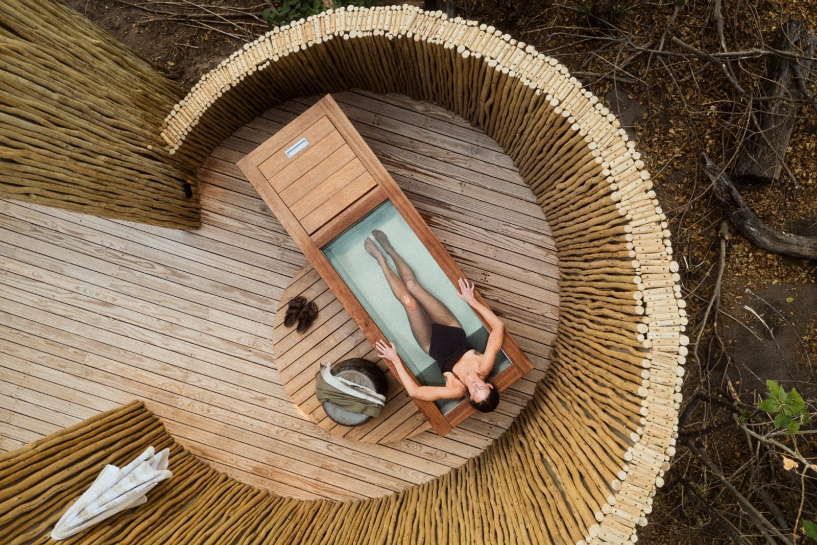 Overhead view of a guest resting on a glass-panelled deck at a luxury bush suite