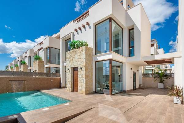 Day exterior view of a white two-storey home with stone detailing, large glazing and a swimming pool
