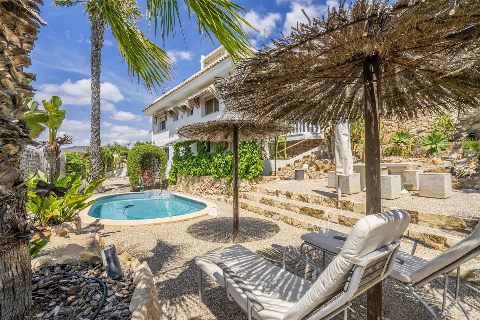 Landscaped garden with pool, loungers and villa exterior