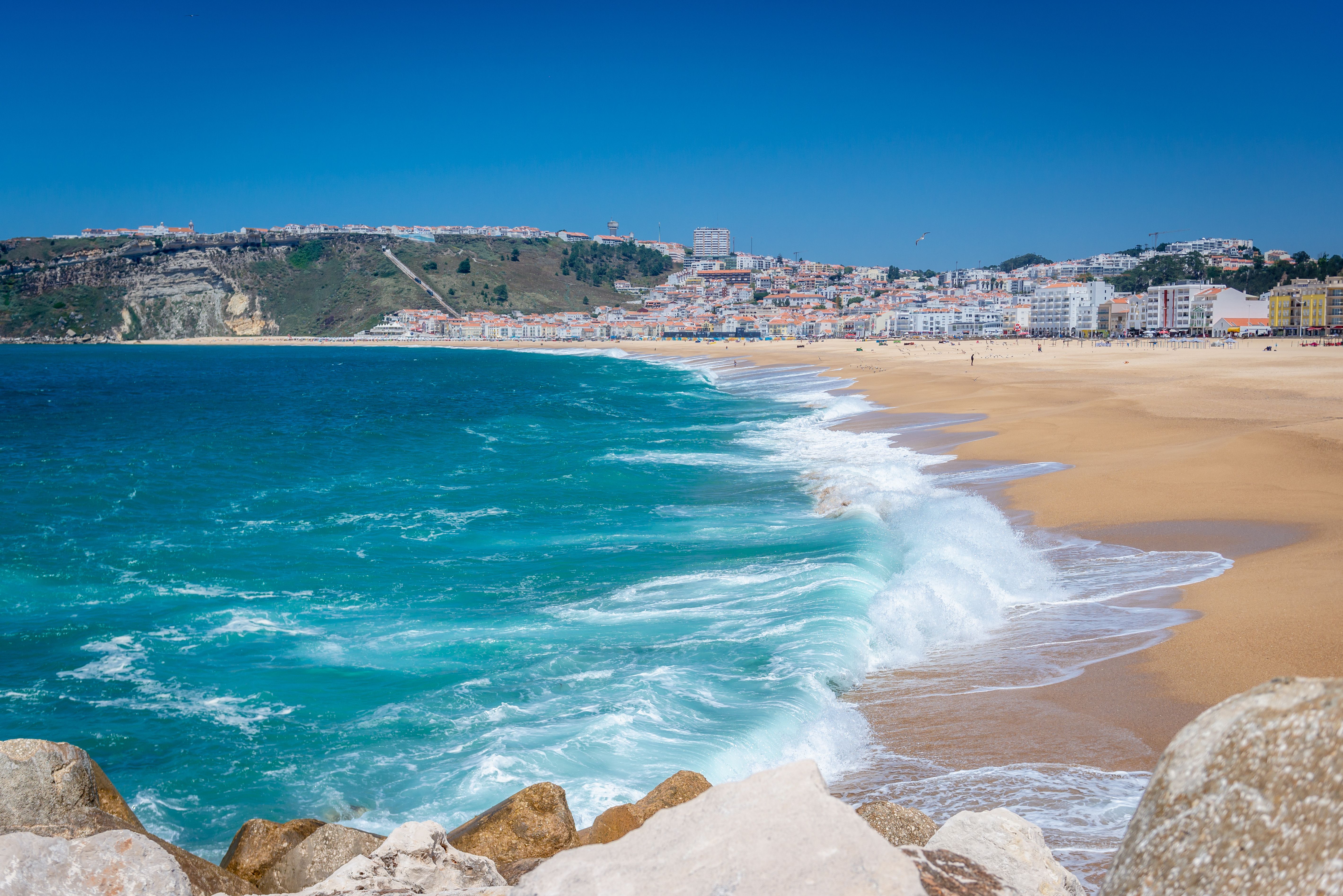 Atlantic waves breaking along a sandy beach, with a coastal town beyond