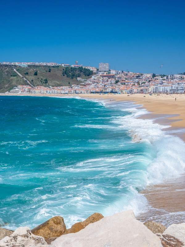 Atlantic waves breaking along a sandy beach, with a coastal town beyond