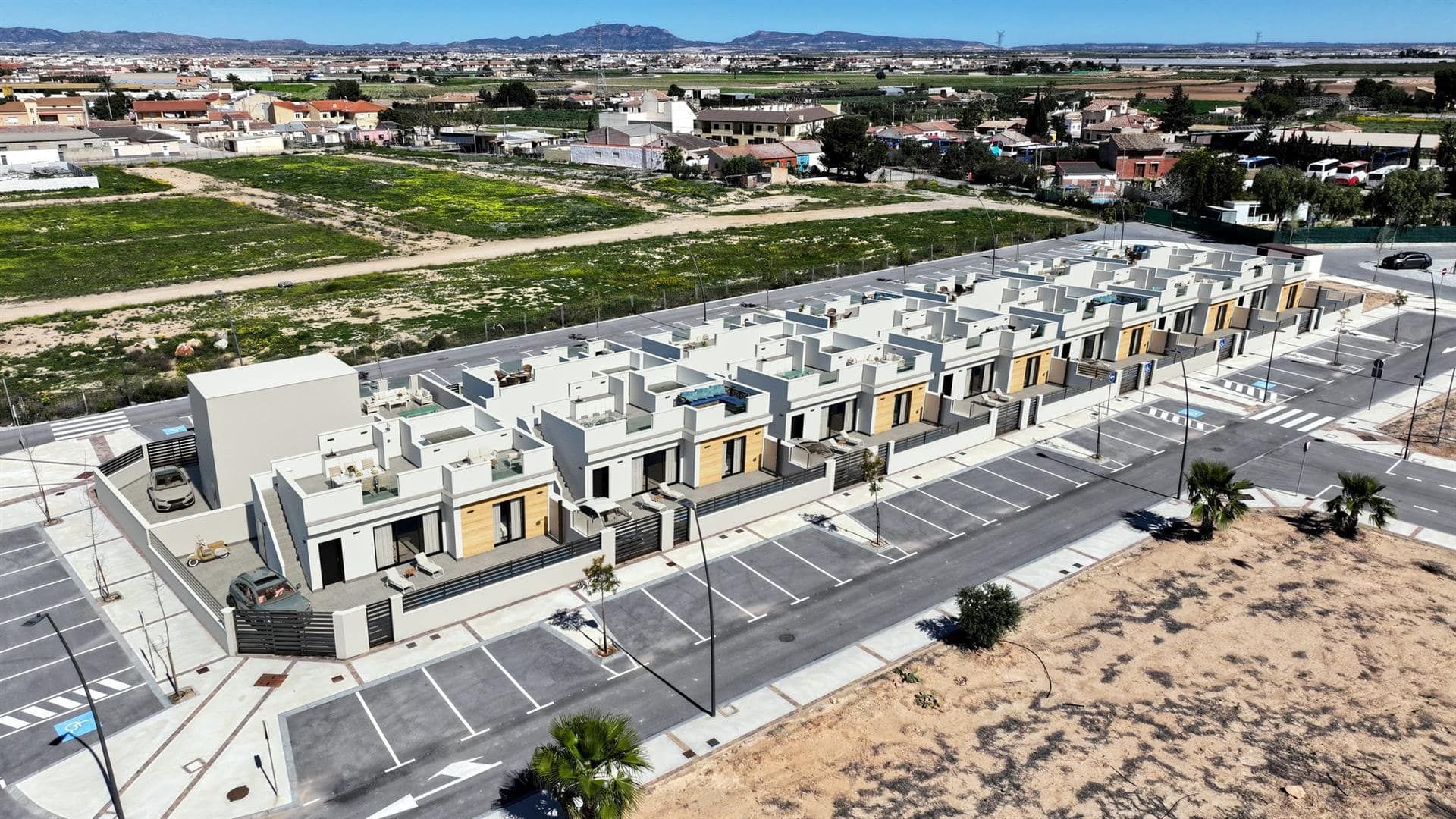 Aerial view of a row of white contemporary homes within a wider low-rise area