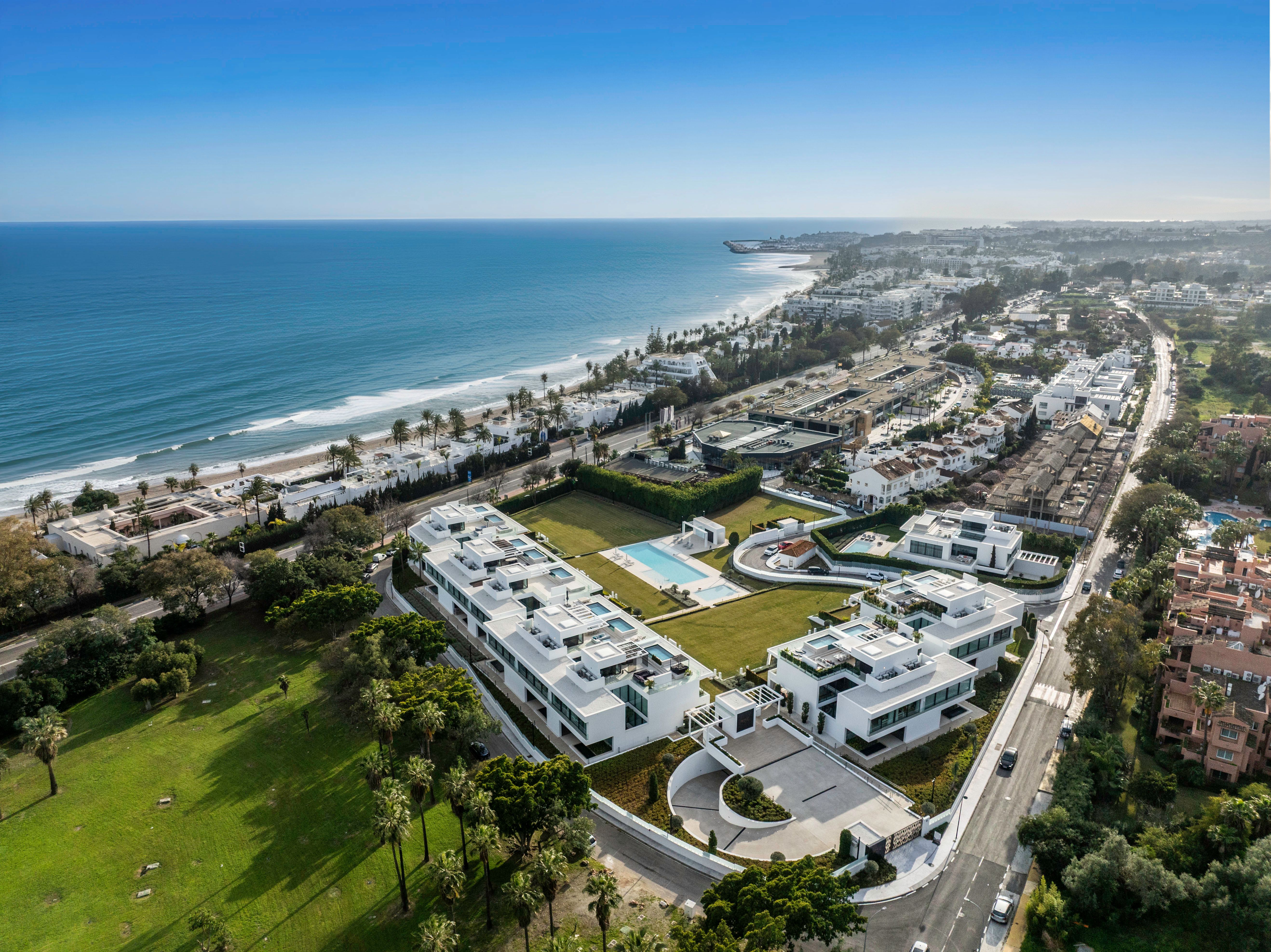 Aerial coastal view showing the villa setting between golf greenery and the shoreline.