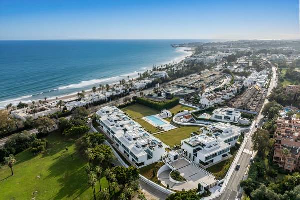 Aerial coastal view showing the villa setting between golf greenery and the shoreline.