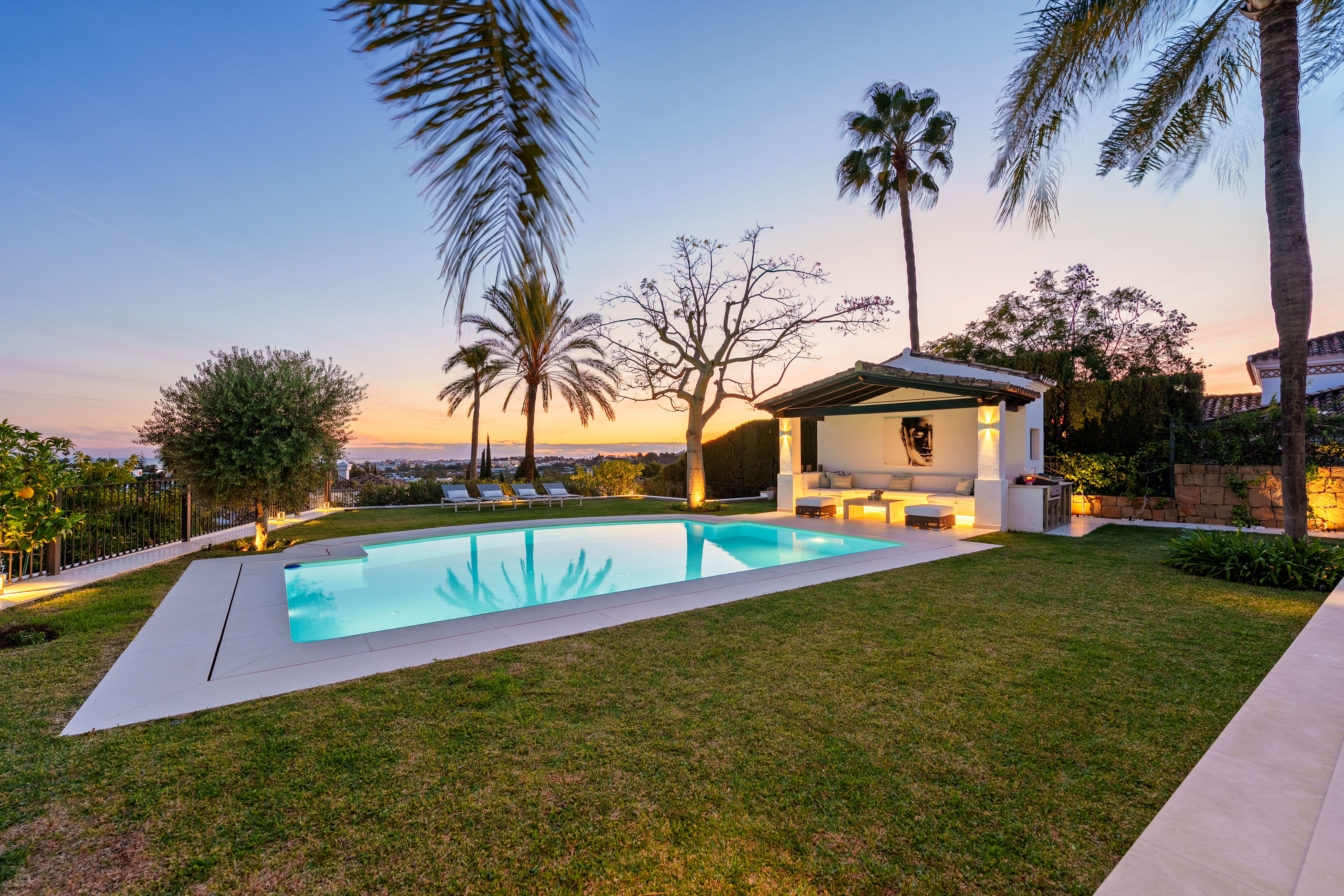 Villa La Perla's garden, pool and poolside pavilion at dusk, with the Mediterranean on the horizon