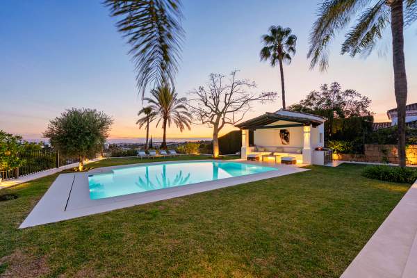 Villa La Perla's garden, pool and poolside pavilion at dusk, with the Mediterranean on the horizon