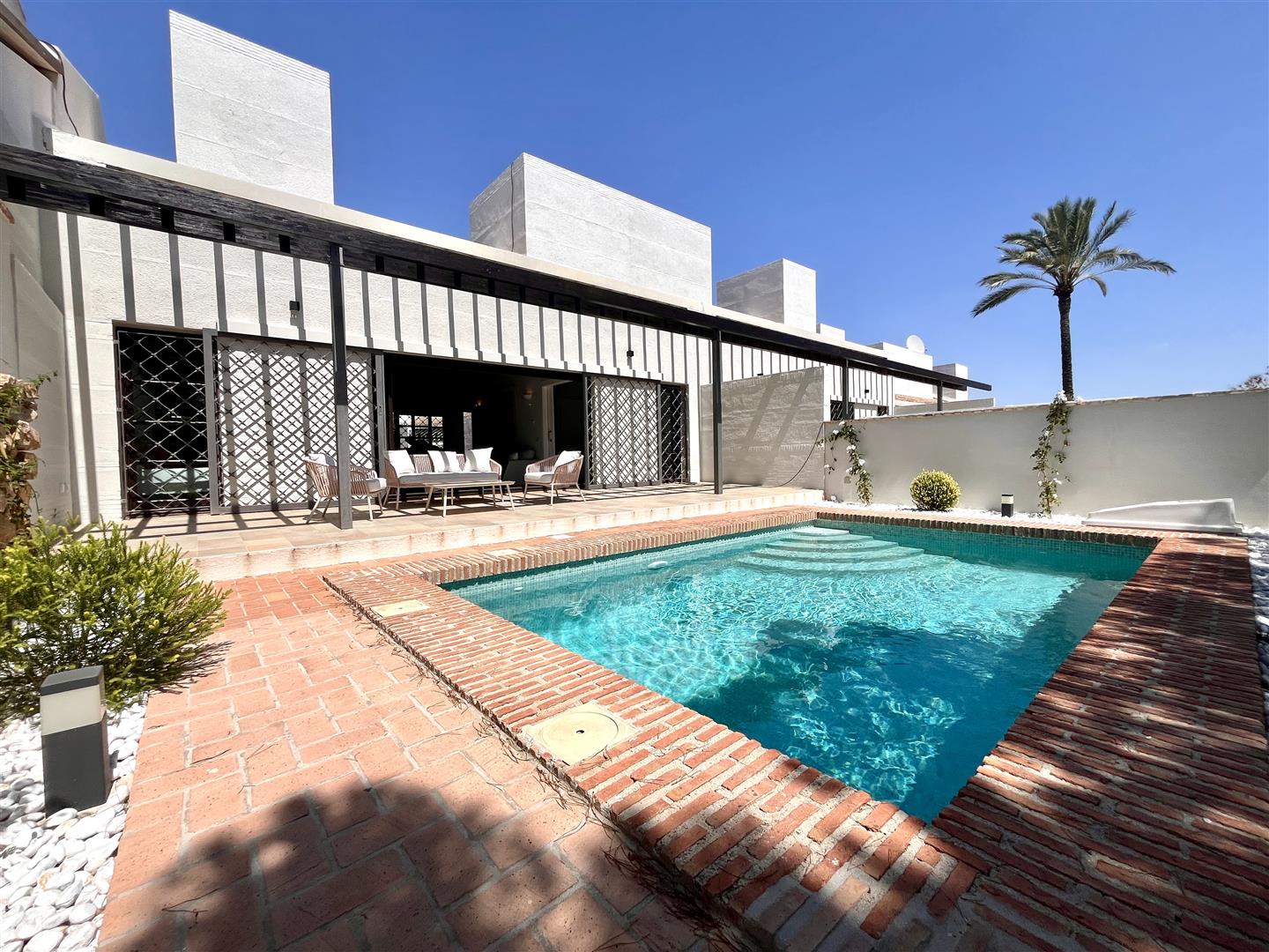 Private courtyard with swimming pool beside a white Mediterranean-style home