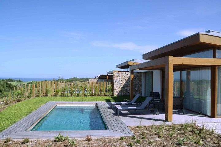 Single-storey villa with a private pool and timber pergola at West Cliffs, with neighbouring villas, dune planting and the Atlantic on the horizon