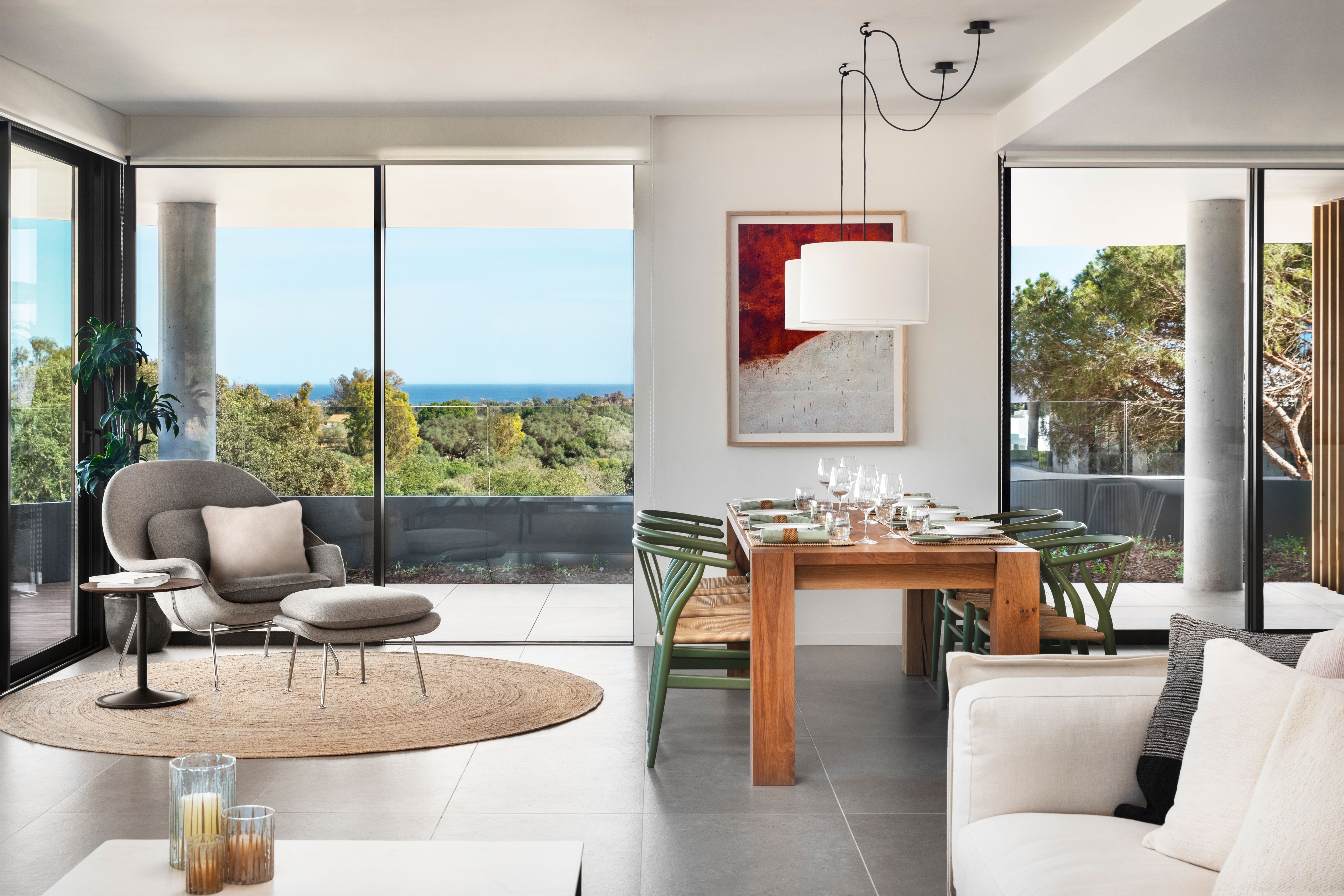 Open-plan Village Verde living and dining area opening towards a wooded terrace outlook.