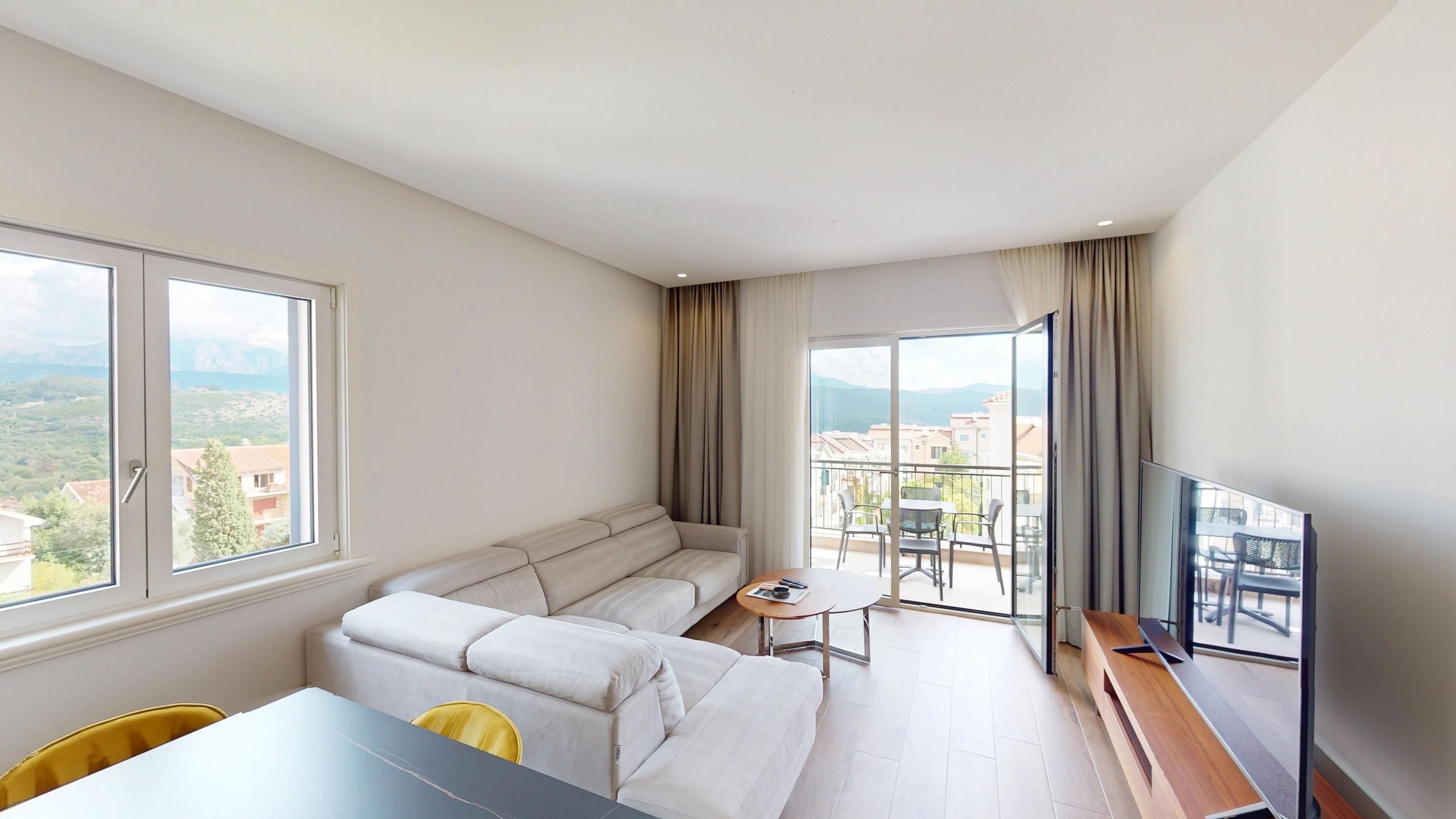 Open-plan living and dining room opening to a balcony with village and mountain views at Apartment 3b321 in Centrale, Luštica Bay